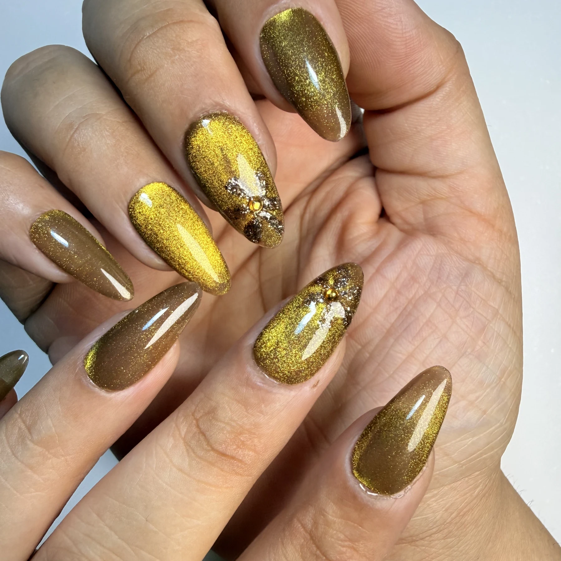 Liquid Gold hand-painted cat-eye press-on nails with golden glitter floral detailing